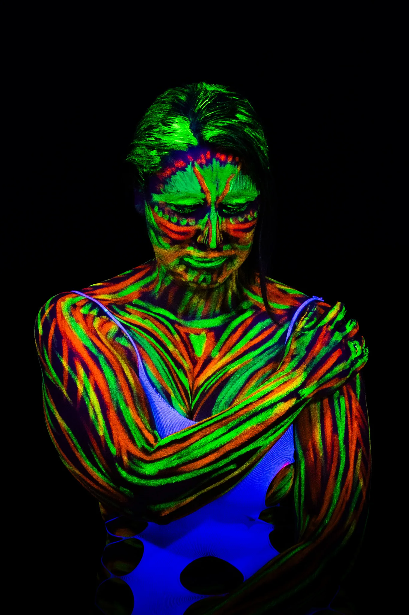 Farbshooting: UV-Bodypainting mit leuchtenden Streifen in Grün, Rot und Orange auf Armen und Gesicht