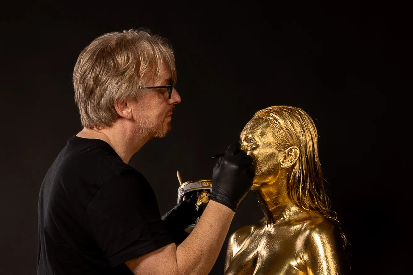 Making-of eines Goldshootings: Marcus Beelitz trägt die Goldfarbe im Gesicht auf