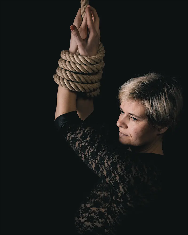 Frau, um deren Unterarme ein Seil gelegt ist